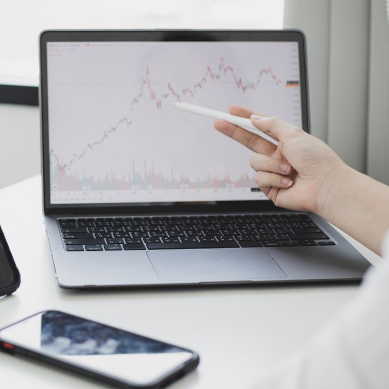Main pointant un graphique boursier affiché sur un ordinateur portable lors d’une analyse des marchés financiers Main pointant un graphique boursier affiché sur un ordinateur portable lors d’une analyse des marchés financiers